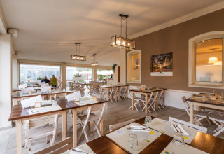 Indretning af familievenlig restaurant med træborde på Vigna sul Mar Family Camping Village, Emilia-Romagna.