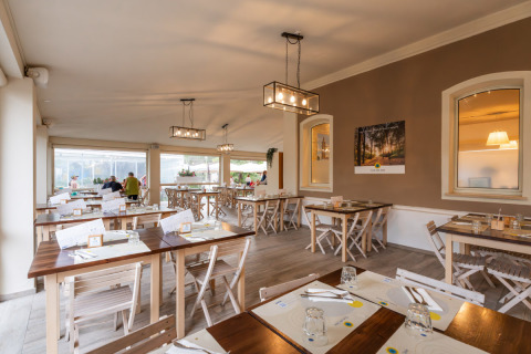 Indretning af familievenlig restaurant med træborde på Vigna sul Mar Family Camping Village, Emilia-Romagna.