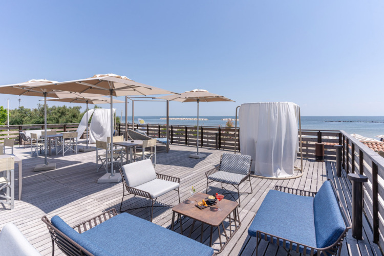 Dakterras met comfortabele zitplaatsen, parasols en zeezicht bij Vigna sul Mar Family Camping Village.