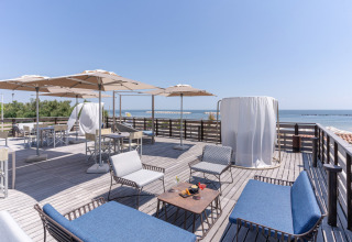 Terraza en la azotea con asientos cómodos, sombrillas y vista al mar en Vigna sul Mar Family Camping Village.