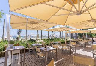 Außenterrasse eines Restaurants mit Sonnenschirmen im Vigna sul Mar Family Camping Village, Emilia-Romagna, Italien.