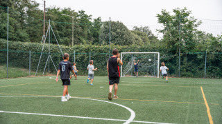 Niños y un adulto juegan al fútbol en un campo verde en Vigna sul Mar Family Camping Village, Italia.