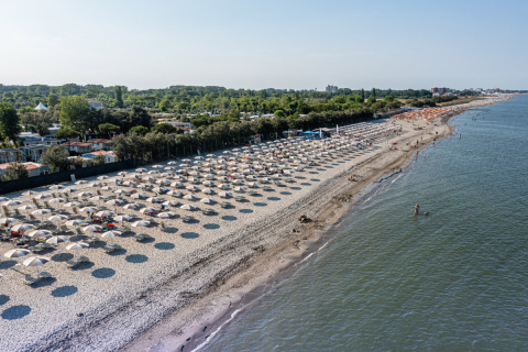 Vista aérea de la playa en Vigna sul Mar Family Camping Village en Emilia-Romaña, Italia, con sombrillas.