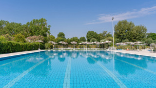 Gran piscina al aire libre en Vigna sul Mar Family Camping Village en Emilia-Romaña, rodeada de sombrillas.
