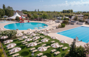 Piscinas al aire libre y tumbonas con sombrillas en Vigna sul Mar Family Camping Village en Emilia-Romaña, Italia.