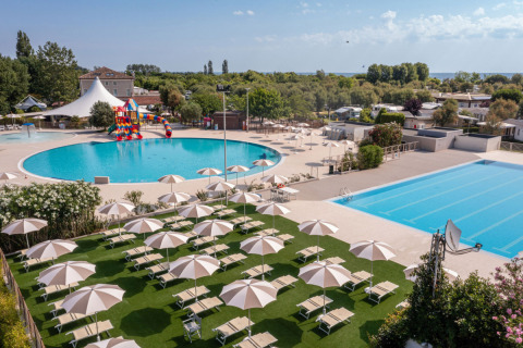 Outdoor pools with loungers and umbrellas at Vigna sul Mar Family Camping Village in Emilia-Romagna, Italy.