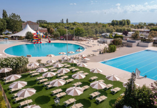 Außenpools und Sonnenliegen mit Sonnenschirmen im Vigna sul Mar Family Camping Village in Emilia-Romagna, Italien.