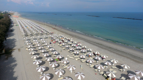 Vista aérea de playa de arena con filas de sombrillas en Vigna sul Mar Family Camping Village, Emilia-Romaña, Italia.