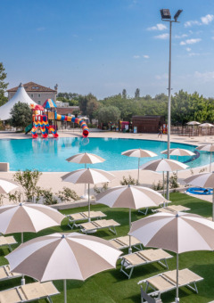 Área exterior de piscina con tumbonas y sombrillas en Vigna sul Mar Family Camping Village, Italia.