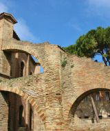Ruinas de ladrillo con arcos y ventanas, rodeadas de árboles bajo un cielo azul cerca de Lido di Pomposa.