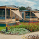 Moderne Tiny Lodge ved Holiday park De Boshoek i Holland med træveranda og farverige blomsterbede.