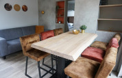 Dining area with wooden table, cozy chairs, and sofa in Family Lodge at Holiday park De Boshoek, Netherlands.