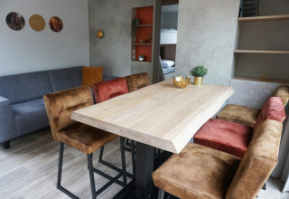Espace repas avec table en bois et fauteuils confortables à la Family Lodge, Holiday park De Boshoek, Pays-Bas.