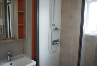 Baño moderno con ducha, espejo, lavabo y ventana en Family Lodge en De Boshoek, Países Bajos.