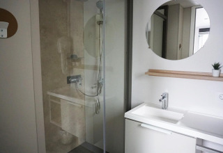 Modern bathroom with shower and white sink at Family Lodge in Holiday park De Boshoek, Netherlands.