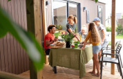 Familie isst gemeinsam auf einer Terrasse einer Family Lodge im Holiday park De Boshoek, Niederlande.