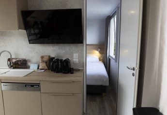 Moderna cocina de lodge con fregadero y electrodomésticos, puerta abierta muestra dormitorio acogedor.