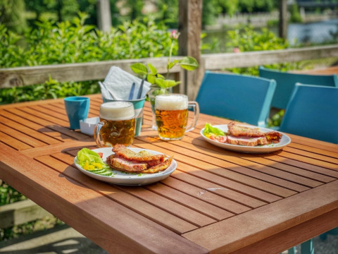 Mesa al aire libre con dos cervezas, sándwiches y verduras en Camping Prima, parque vacacional en Bohemia del Sur, Chequia.