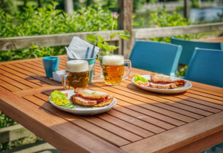 Tavolo all'aperto con due birre, panini e verdure al Camping Prima, parco vacanze in Boemia Meridionale, Repubblica Ceca.