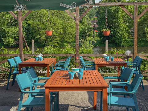Gezellige buitenzitplaats met blauwe stoelen en houten tafels bij Camping Prima, Zuid-Bohemen.