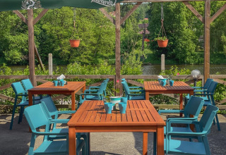 Terraza al aire libre con sillas azules y mesas de madera en Camping Prima, Sur de Bohemia, Chequia.