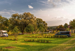 Feriepark Camping Prima i Sydbøhmen, Tjekkiet, med grønne plæner, træer, autocamper og minibus.