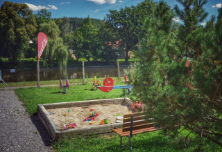 Legeplads med sandkasse, bænke og farverige legeredskaber på Camping Prima i Sydbøhmen, Tjekkiet.
