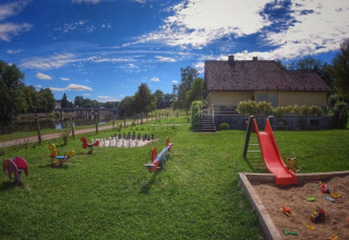 Legeplads ved et sommerhus på Camping Prima i Sydbøhmen, Tjekkiet med rutsjebane, sandkasse og legetøj.