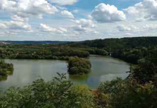 Uitzicht over een rustige rivier en groene bossen vanaf Camping Prima in Zuid-Bohemen, Tsjechië onder de blauwe lucht.