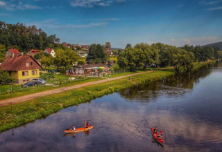 Two canoes float on a calm lake by Camping Prima, lined with houses and trees in South-Bohemia, Czech Republic.