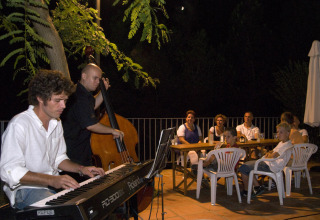 Live muziekoptreden 's avonds op Vilanova Park Camping, Catalonië, met gasten genietend op het terras.