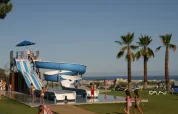 Børn leger ved en vandrutsjebane og pool på Vilanova Park Campingplads i Catalonien, Spanien.