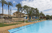 Piscina all'aperto con lettini e palme al campeggio Vilanova Park in Catalogna, Spagna.