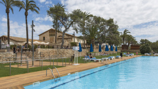 Piscina exterior con tumbonas y palmeras en el camping Vilanova Park de Cataluña, España.