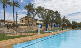Udendørs swimmingpool med liggestole og palmer på Vilanova Park Campingplads i Catalonien, Spanien.