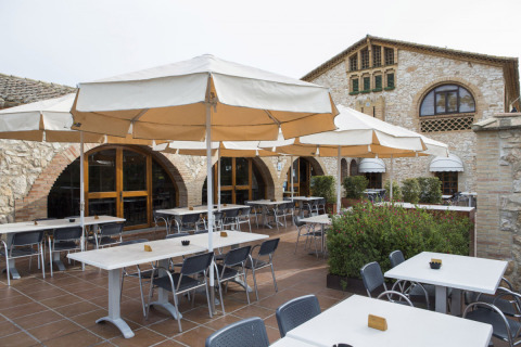 Terraza con sombrillas y mesas en Vilanova Park Campsite, un parque vacacional en Cataluña, España.