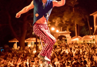 Un artista su un monociclo si esibisce davanti a una grande folla al Vilanova Park Campsite in Catalogna, Spagna.