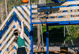 Jonge vrouw springt om een basketbal te gooien op het buitenterrein van Vilanova Park in Catalonië, Spanje.