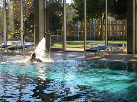 Indoor swimming pool with loungers and garden view at Vilanova Park Campsite in Catalonia, Spain.