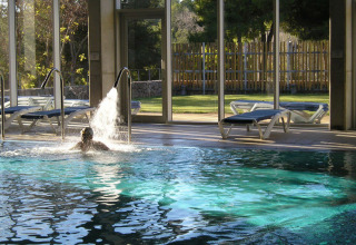 Indoor swimming pool with loungers and garden view at Vilanova Park Campsite in Catalonia, Spain.