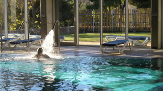 Piscina cubierta con tumbonas y vistas al jardín en el camping Vilanova Park, Cataluña, España.