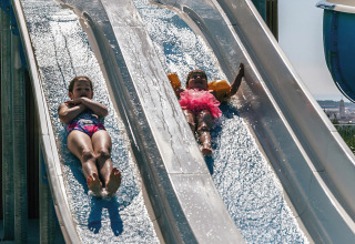Due bambini scivolano sugli scivoli d’acqua al campeggio Vilanova Park, Catalogna, Spagna, in una giornata di sole.