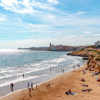 Personas disfrutando de la playa cerca de Vilanova i la Geltrú, Cataluña, España, con la ciudad al fondo.