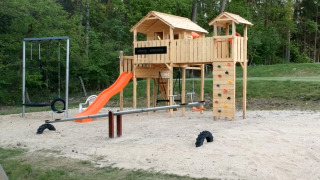 Speeltuin bij Camping Sonnenberg, Nedersaksen, Duitsland met glijbaan, schommels en klimwand.