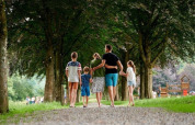 Una familia pasea de la mano por un sendero arbolado en el Camping Village Sy en Lieja, Bélgica.