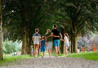 Familie spaziert gemeinsam einen bewaldeten Weg entlang im Camping Village Sy, Lüttich, Belgien.