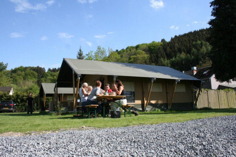 Famille pique-nique devant une tente au Camping Village Sy, parc de vacances à Liège, Belgique, nature luxuriante.