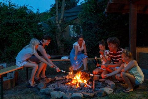 Familie röstet Marshmallows am Lagerfeuer im Camping Village Sy, Ferienpark in Lüttich, Belgien.