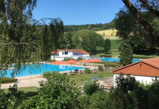 View of the pool area at Camping Walsheim holiday park in Saarland, Germany, surrounded by lush countryside.