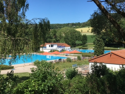 View of the pool area at Camping Walsheim holiday park in Saarland, Germany, surrounded by lush countryside.